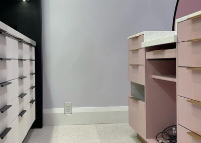 Blush retail cabinetry with brass pulls and white fluted drawer units, beauty store