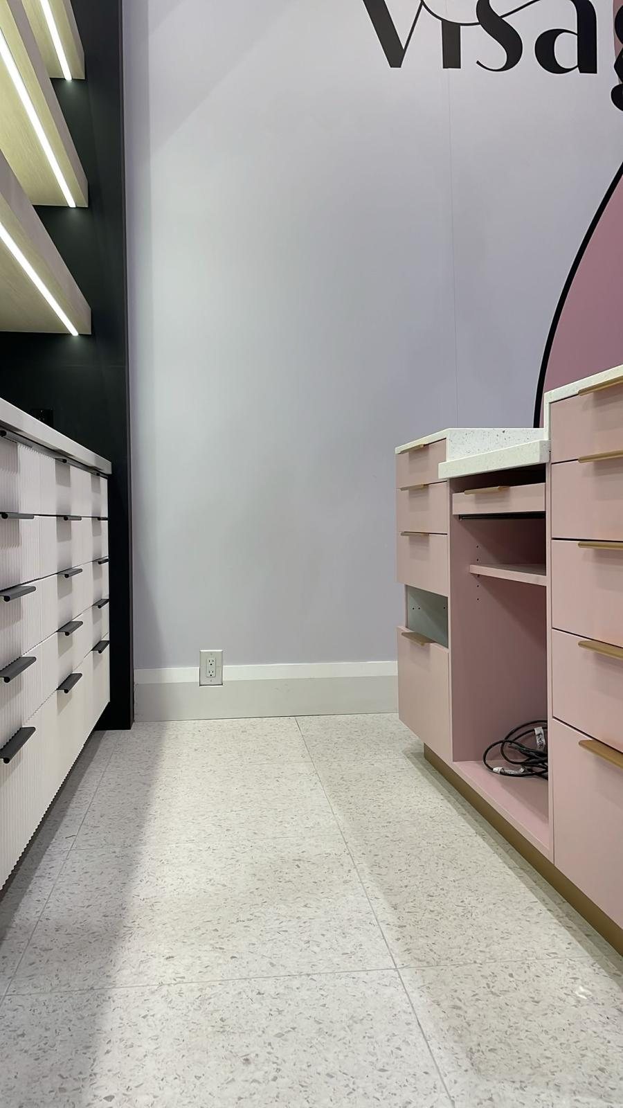 Blush retail cabinetry with brass pulls and white fluted drawer units, beauty store