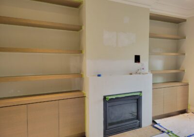 Oak fireplace built-ins with floating shelves and lower cabinets