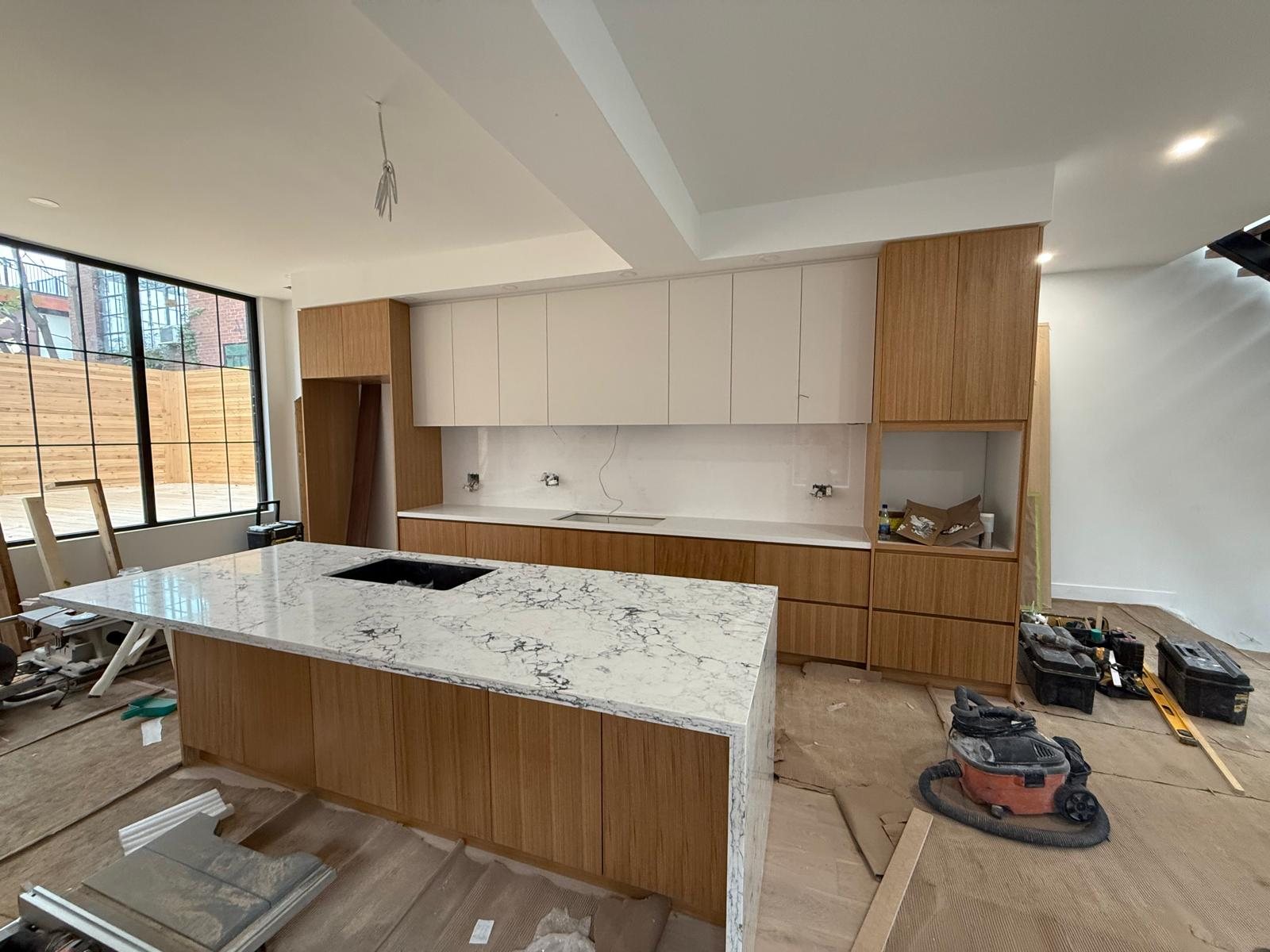 Rift-cut oak kitchen with white uppers and a marble waterfall island, built and installed by Kali Custom Cabinetry, Toronto