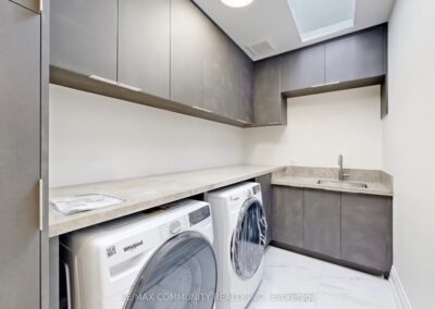 Laundry room built-ins with grey cabinets over the washer and dryer, Toronto