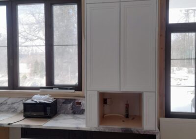 White tall cabinet with mesh doors and an appliance niche