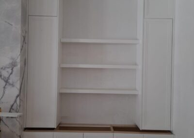 White wall unit with floating shelves and tall cabinets